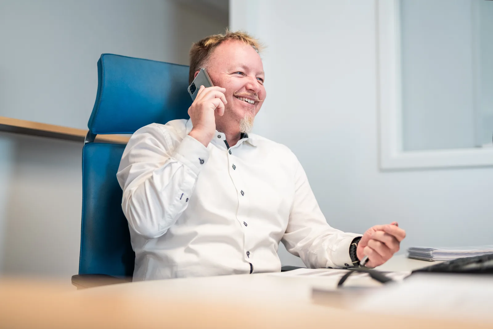 UTB-Mitarbeiter telefoniert am Schreibtisch mit dem Smartphone
