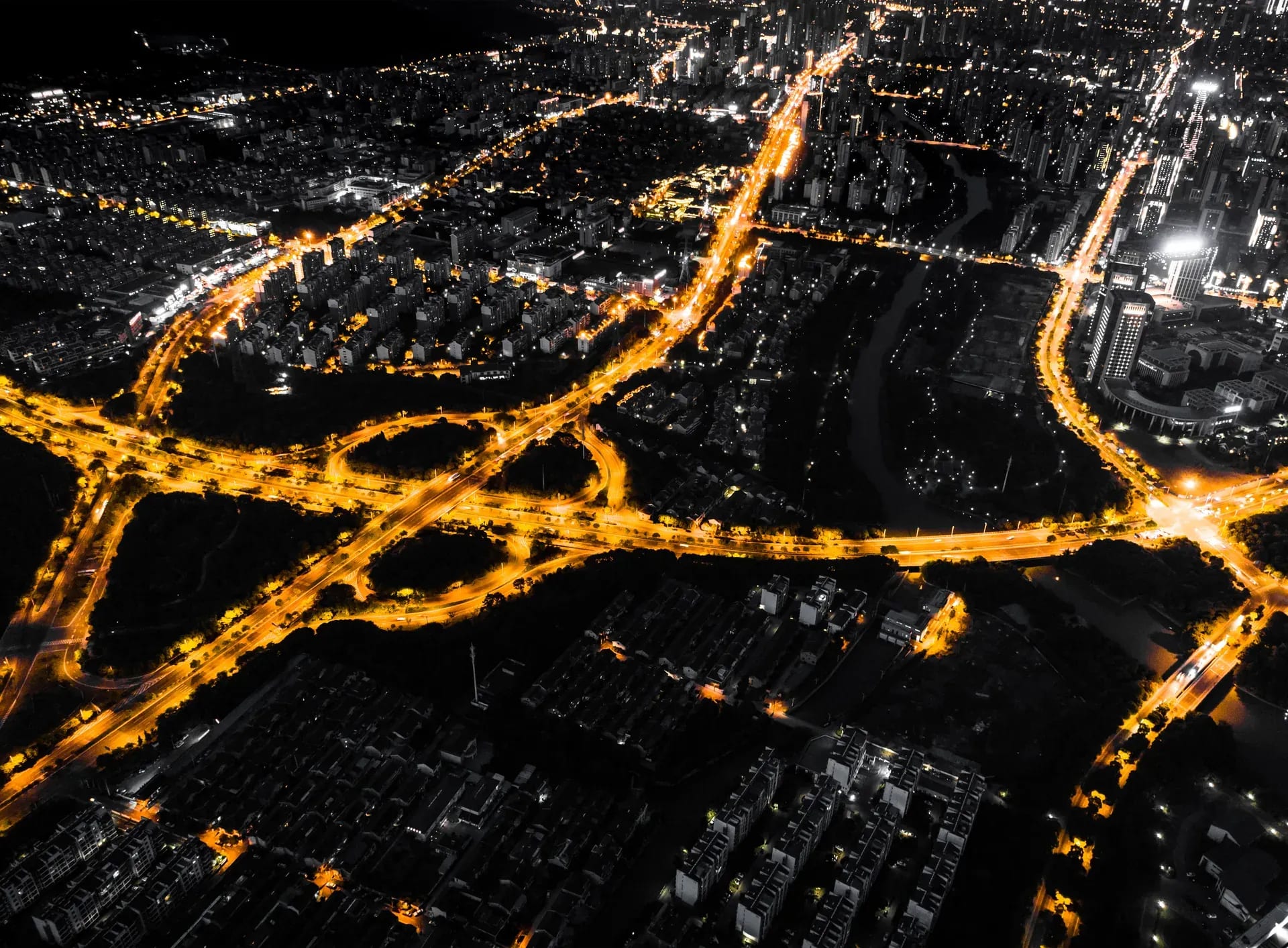 Luftaufnahme einer Stadt bei Nacht mit hell beleuchteten Straßenzügen