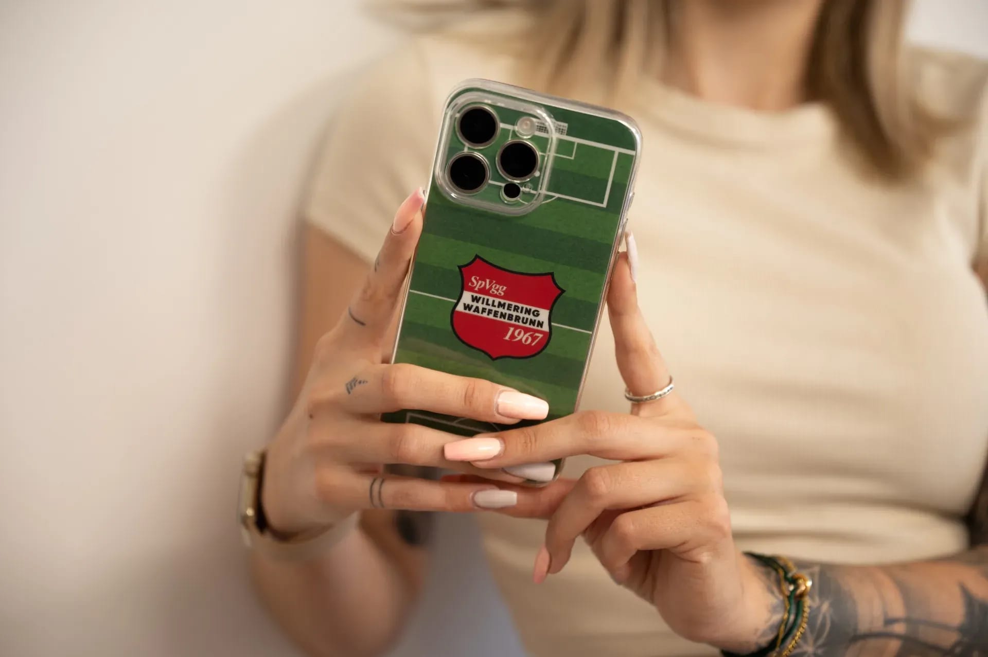 Smartphone mit individuell bedrucktem Backcover: Fußballfeld-Motiv mit dem Wappen der SpVgg Willmering Waffenbrunn